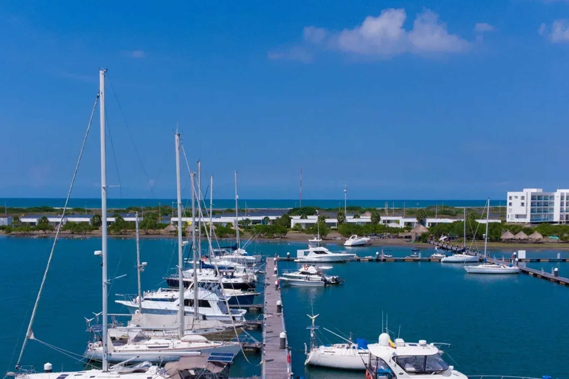 Marina Puerto Velero: Barcos de vela y yates en un muelle con edificios modernos.