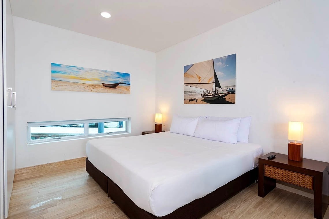 Modern hotel room with queen bed and nautical art at Marina Puerto Velero.