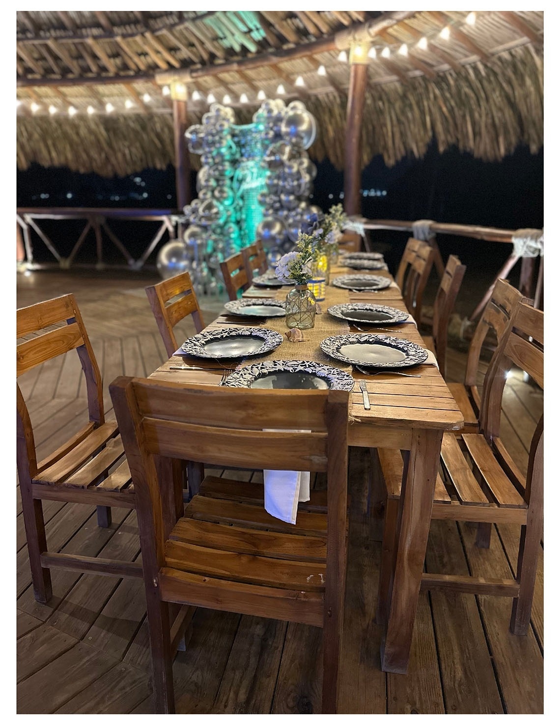 Mesa lista para cena romántica en Marina Puerto Velero, con globos y luces.