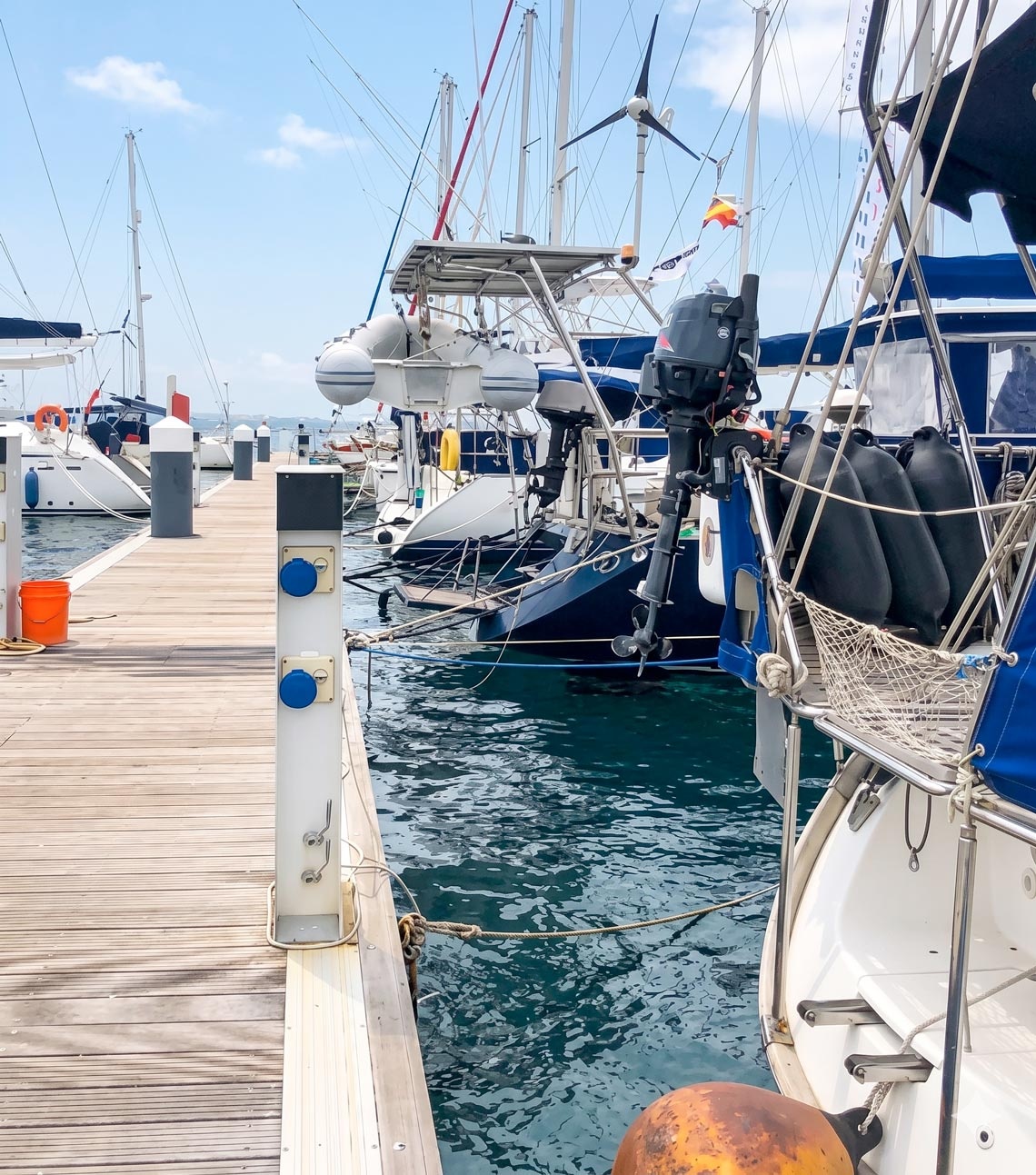 Sailboats docked at Marina Puerto Velero, featuring blue waters and a wooden pier.