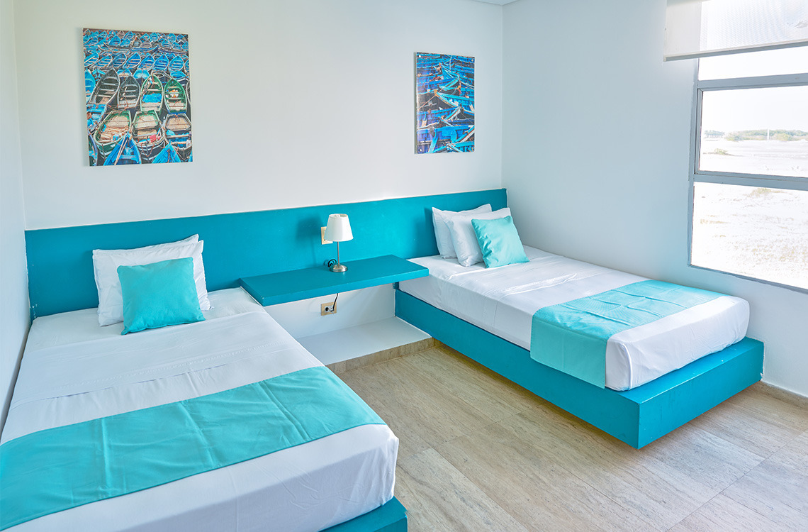 Habitación de hotel con dos camas individuales y decoración náutica, ideal para Marina Puerto Velero.