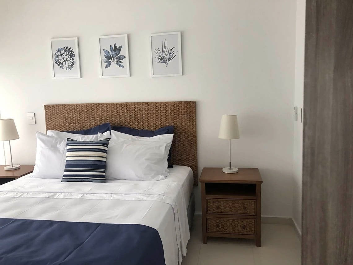 Bedroom with bed, lamp, and coastal art, perfect for Marina Puerto Velero.