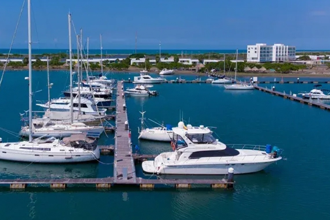 Yachts and sailboats at Marina Puerto Velero, featuring modern hotel and buildings.