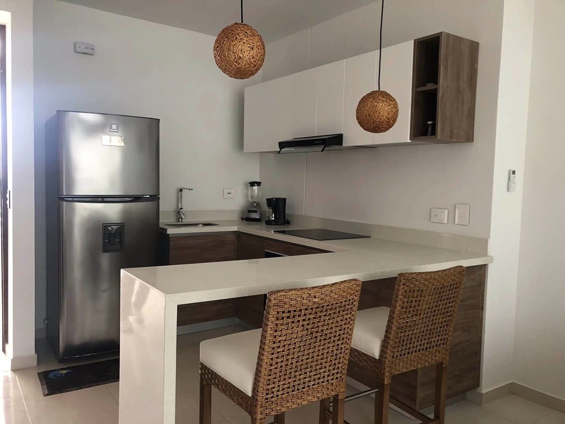 Modern kitchen with stainless steel appliances, quartz island, and stools at Marina Puerto Velero.