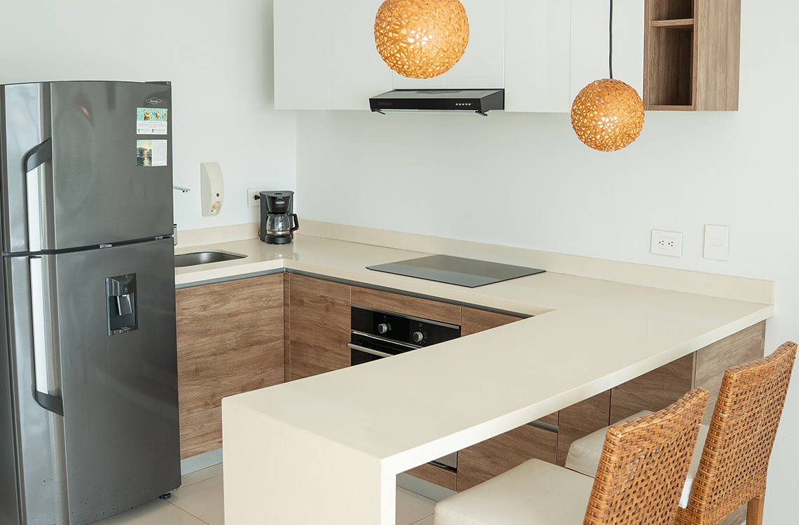 Cocina moderna con Marina Puerto Velero y barra de desayuno, electrodomésticos y dos sillas.