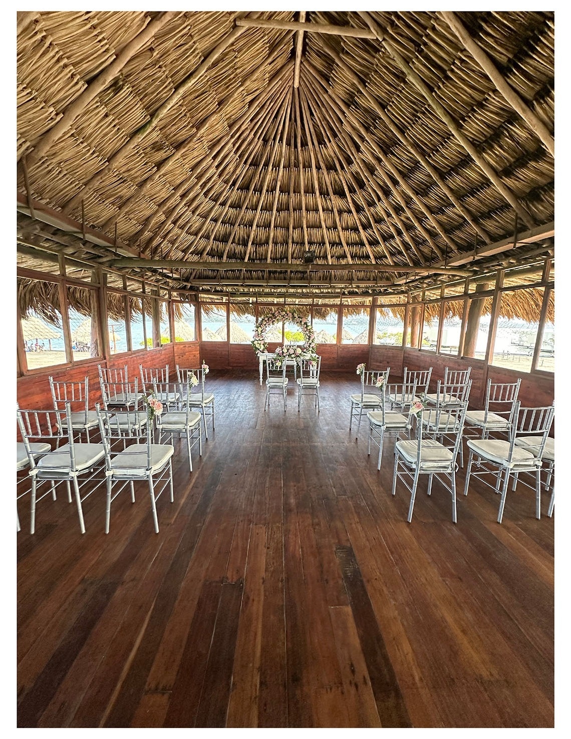 Banquete en Marina Puerto Velero: sillas plateadas y techo de palma.