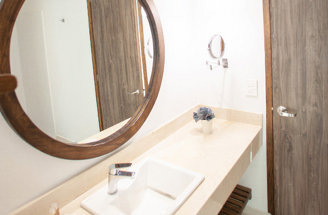 Espejo redondo de madera y lavabo moderno en baño de hotel. Marina Puerto Velero