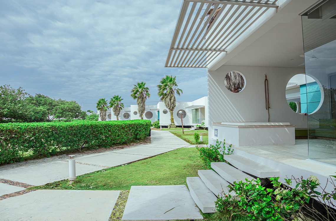 Modern resort bungalows with palm trees and lush landscaping. Marina Puerto Velero
