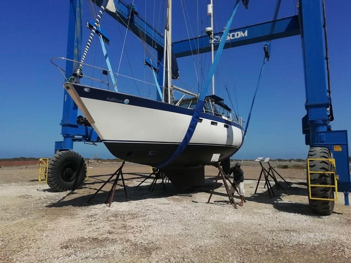 Boat lifted by crane at Marina Puerto Velero, ready for maintenance or launch.