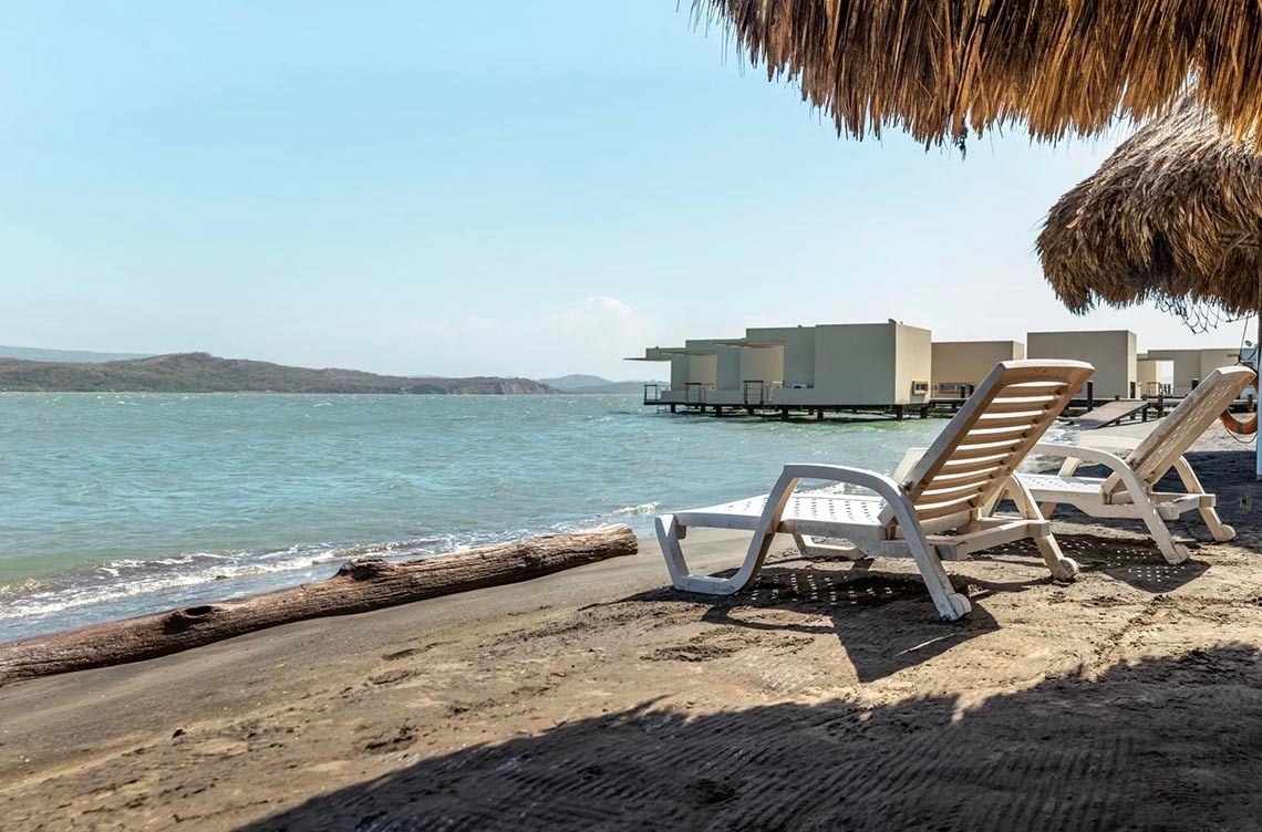 Luxury overwater bungalows at Marina Puerto Velero, with beach loungers.