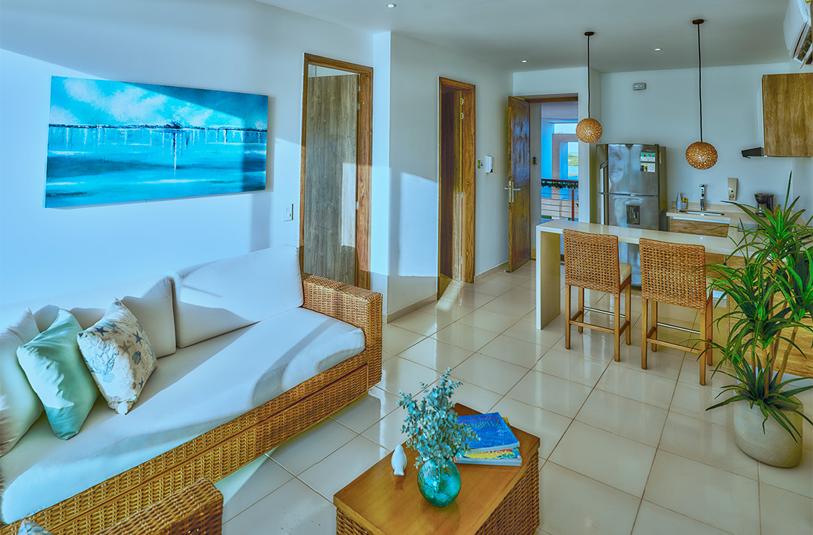 Amplia sala con sofá de mimbre, cocina moderna y vista al mar. Marina Puerto Velero