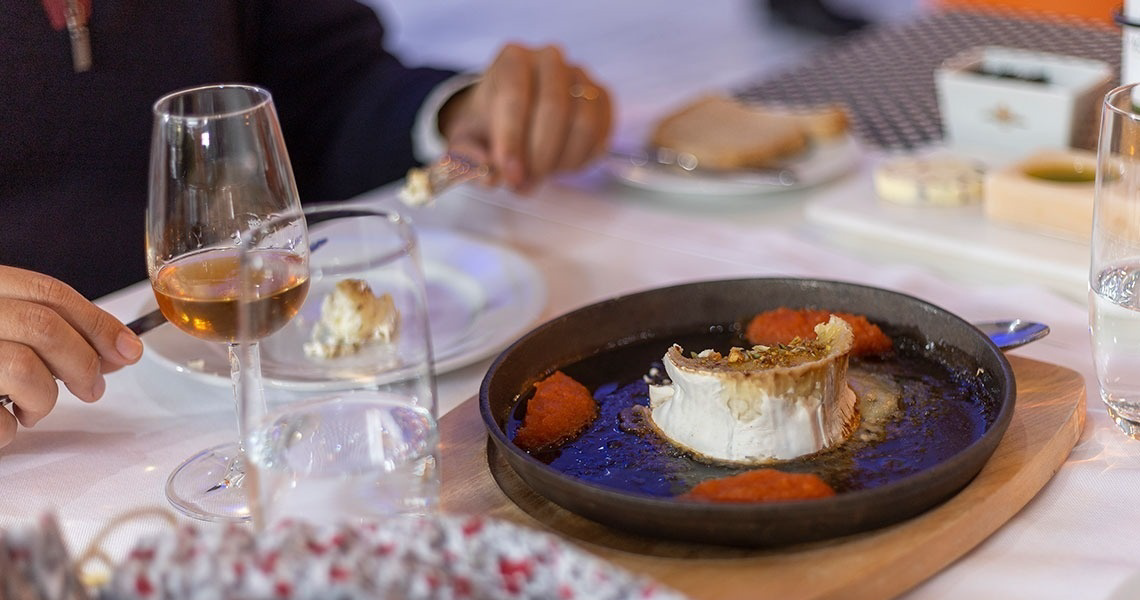 uma pessoa está sentada ao lado de um prato de comida e um copo de vinho