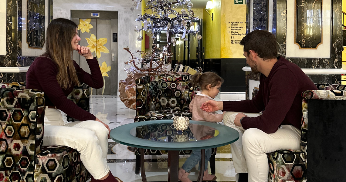 um homem e uma mulher estão sentados ao lado de uma criança em frente a uma árvore de natal