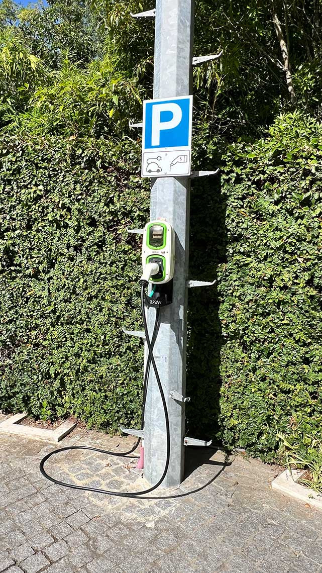 Estação de carregamento de veículos elétricos em estacionamento de hotel com sinal 'Marmoris: Corporative