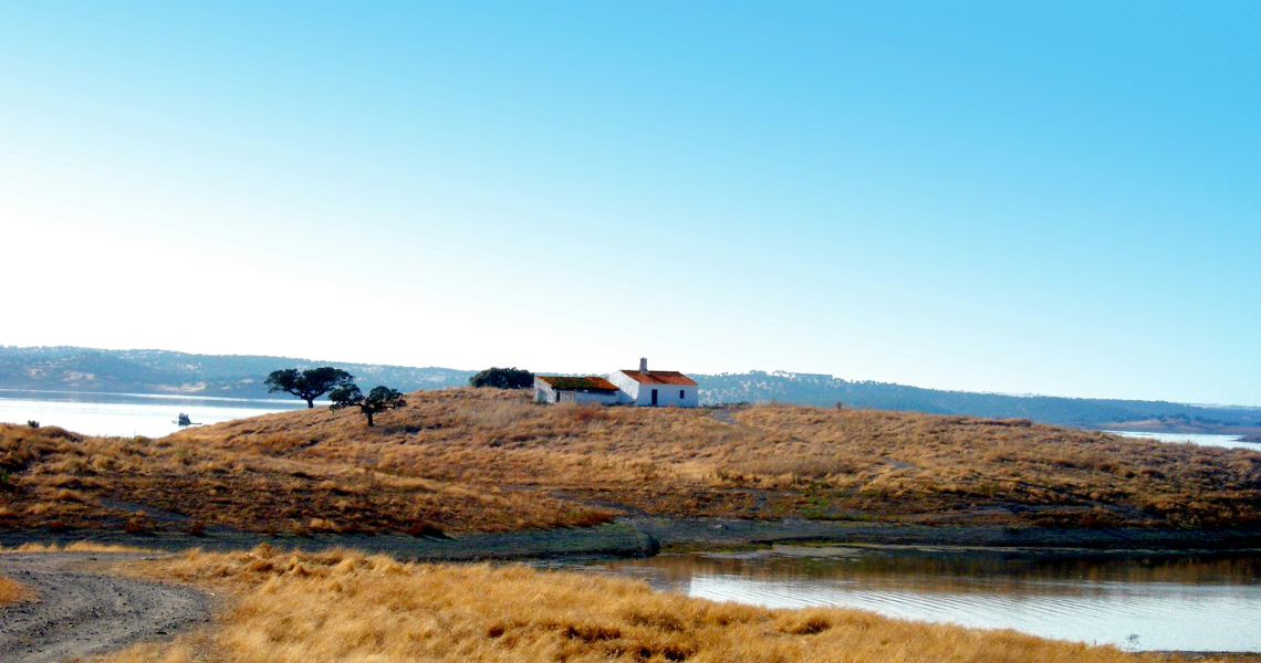 a small house sits on a small hill overlooking a body of water