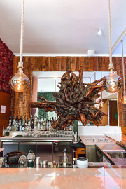 a bar with a large wooden sculpture hanging from the ceiling