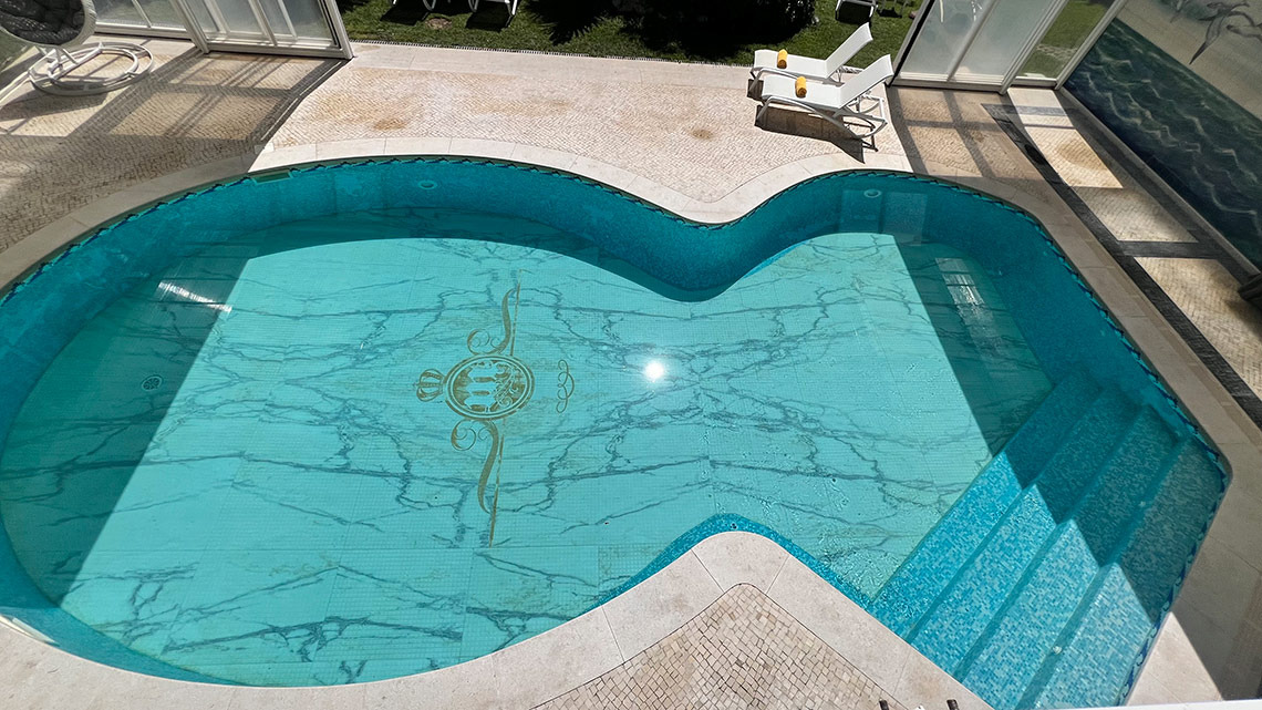 Piscina de hotel Marmoris: Corporative com azulejos azuis e detalhe dourado, deck e espreguiçadeiras ao lado.