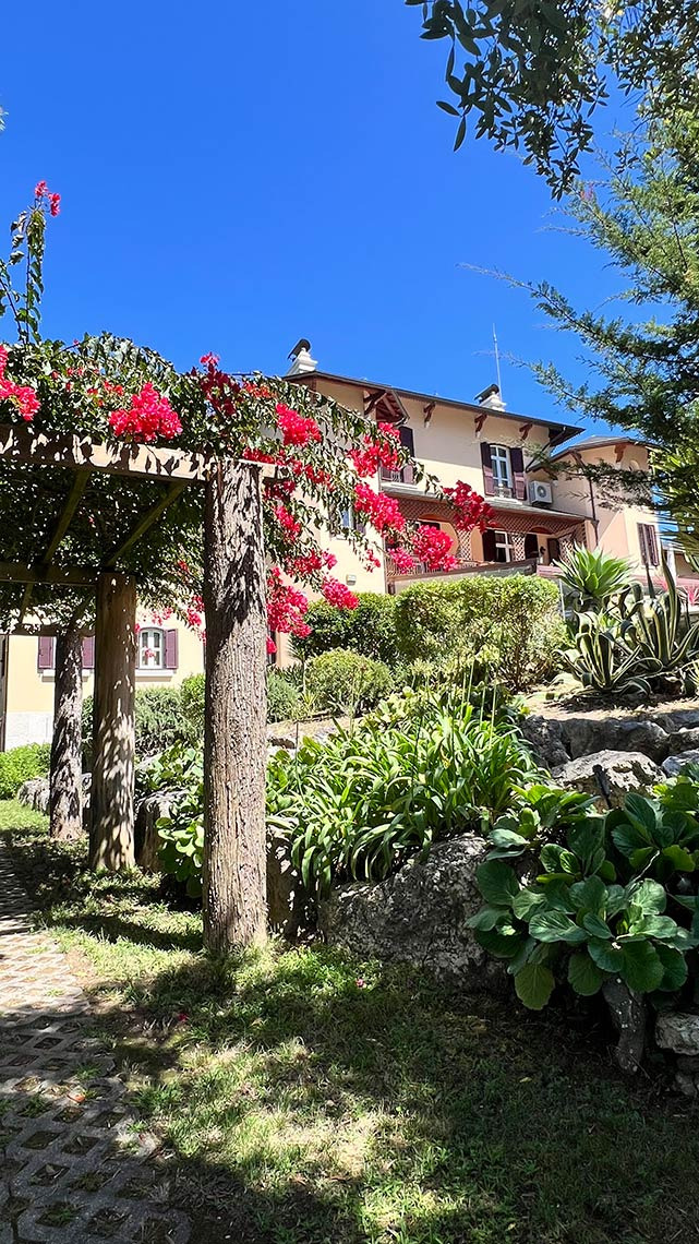 Marmoris: Corporative com flores vermelhas, jardim e casa ao fundo sob o céu azul.