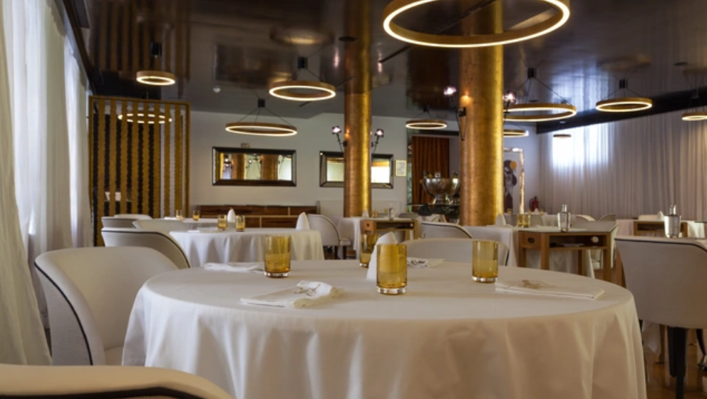 A fachada de um edifício branco exibe um arco central ladeado por murais, um da poetisa Florbela Espanca e outro de asas florais, com calçada portuguesa em primeiro plano.