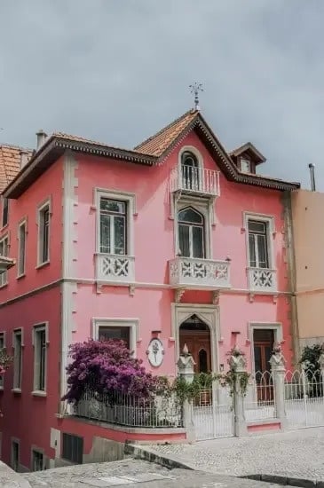 a pink house with a balcony on the top of it .