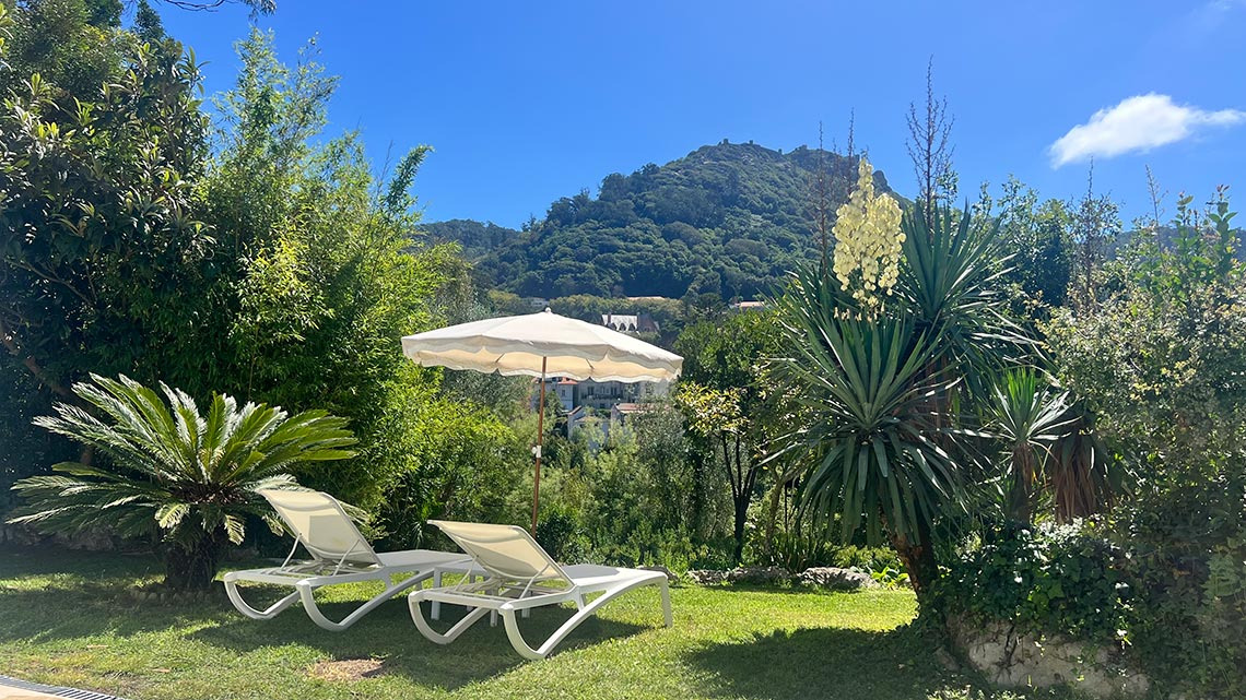 Lounge chairs e guarda-sol em jardim exuberante com vista paraMarmoris: Corporative e montanhas.