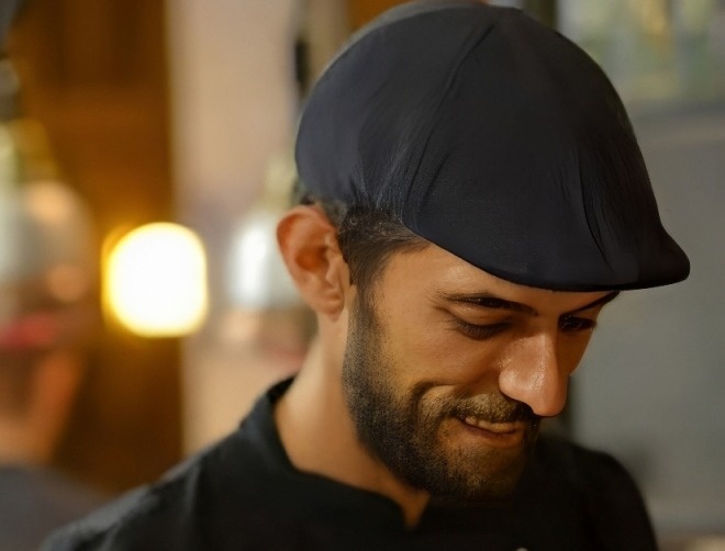 Chef sorrindo com boné e uniforme preto, ideal para Marmoris: Corporative.