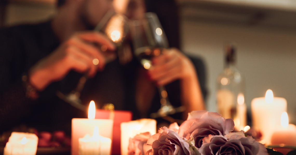 a man and woman are sitting at a table with candles and roses