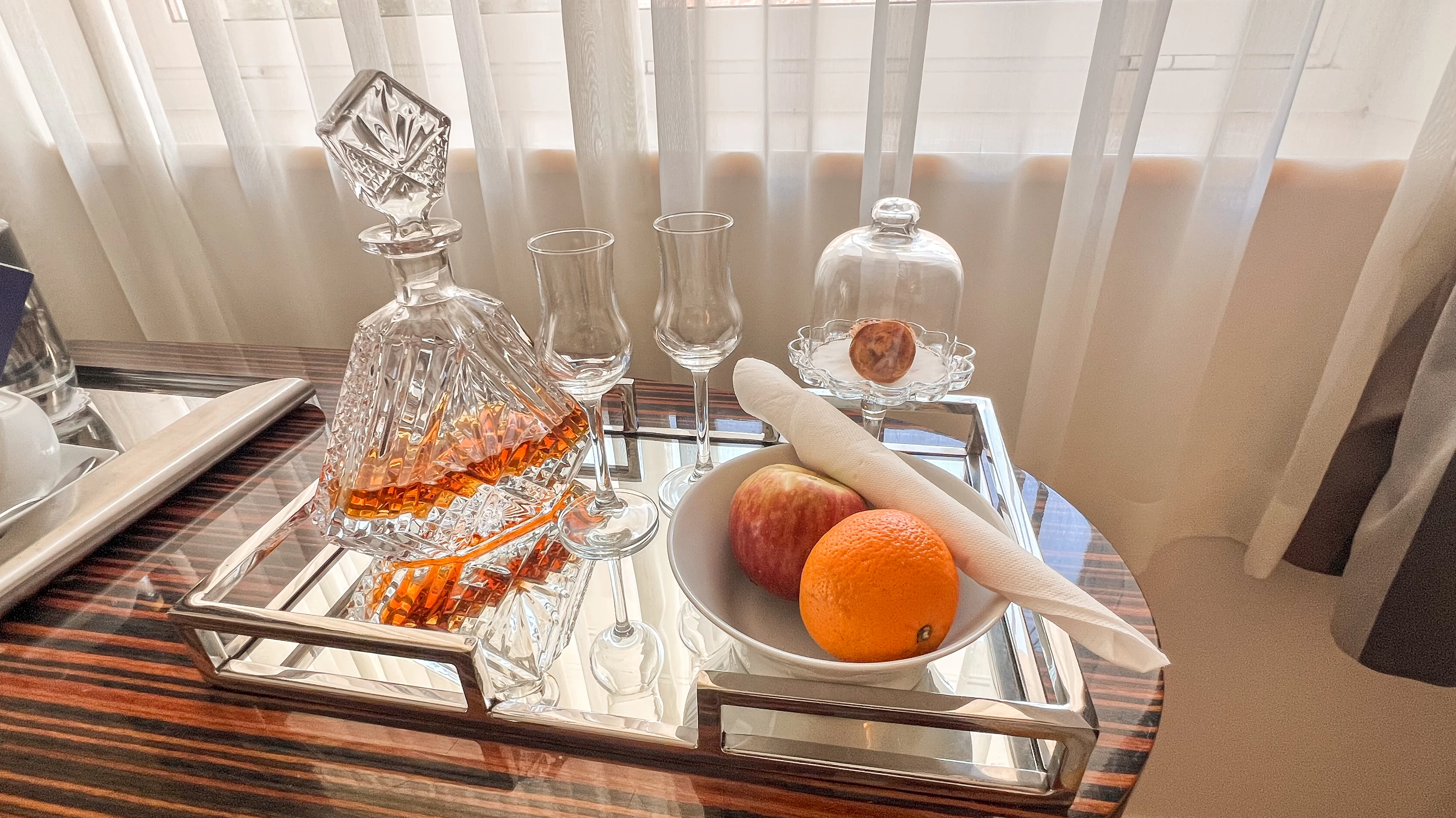 Garrafa de uísque de cristal, taças e frutas em bandeja de serviço de hotel Marmoris Hotels
