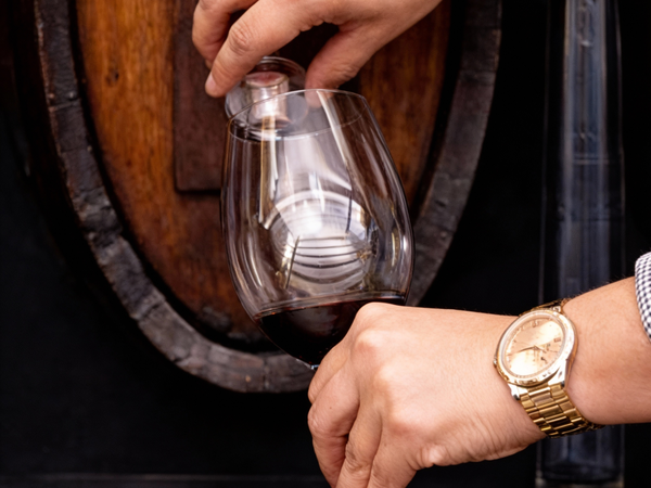 Uma pessoa a tirar vinho de uma pipa para um copo