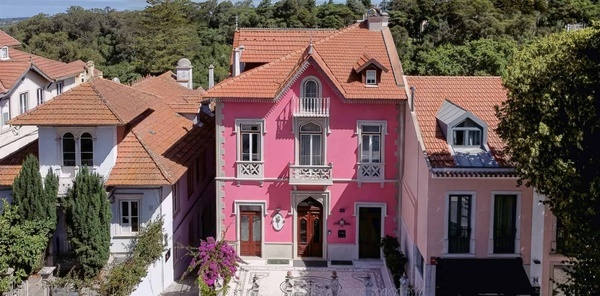 Edifício Marmoris: Corporativo, uma mansão cor-de-rosa com telhados de terracota e floresta exuberante.