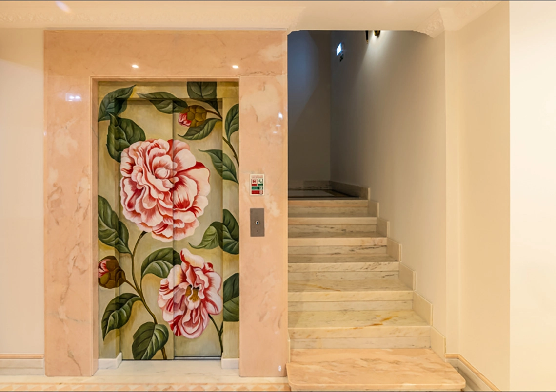 Elegant hotel elevator with floral art and marble stairs. Marmoris Hotels
