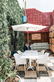 a man sits at a table under an umbrella