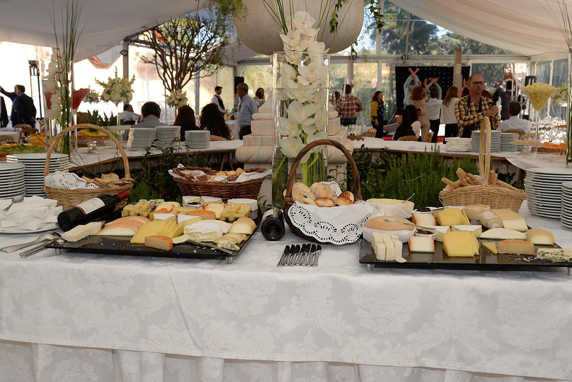 A cheese Marmoris Hotels buffet with assorted cheeses, bread, and wine bottles, set up under a tent.