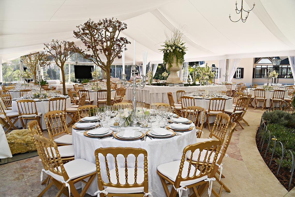 Marmoris: Corporative: Tendas de casamento com mesas decoradas, cadeiras douradas e centros de mesa florais.