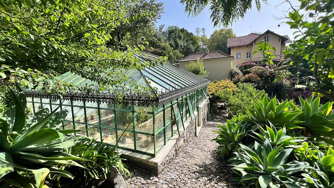 Estufa vitoriana emMarmoris: Corporative, com jardins exuberantes e casa ao fundo.