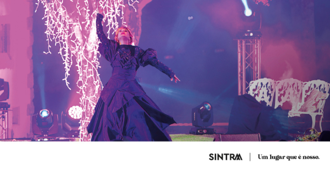 uma mulher em um vestido roxo está em um palco com sintra ao fundo