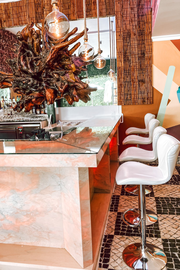 a row of white bar stools in front of a bar