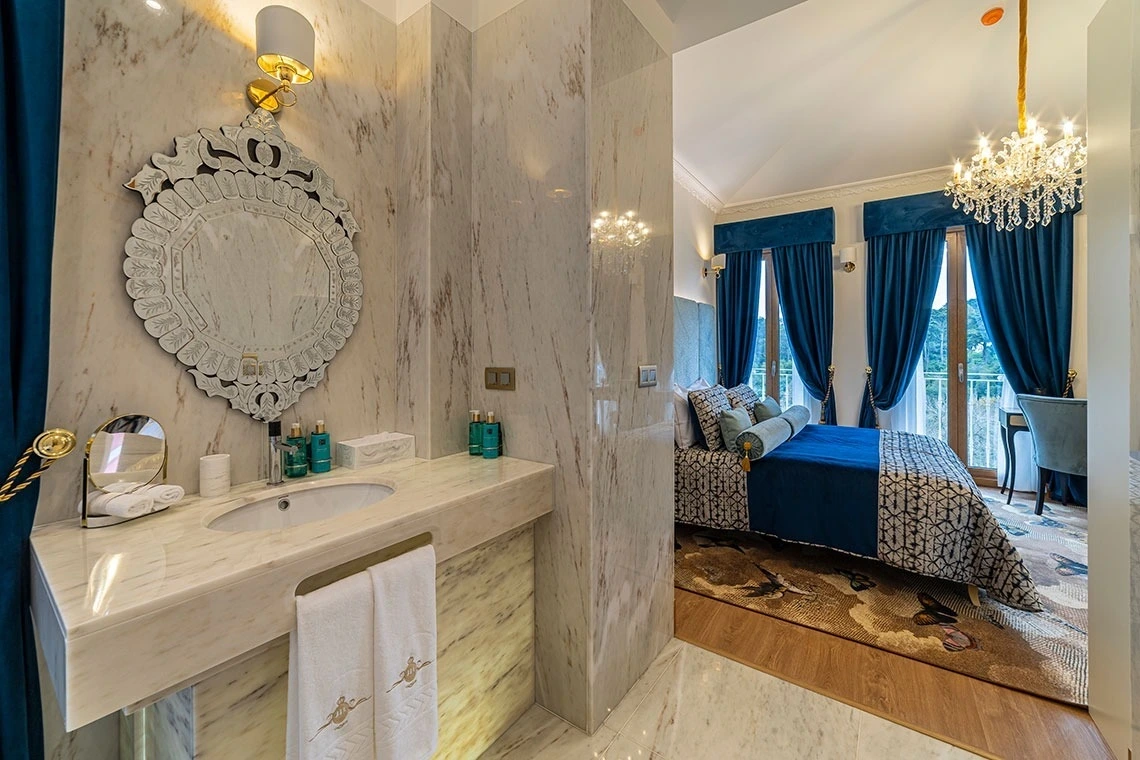 Luxuoso quarto de hotel e banheiro em mármore com decoração em azul. Marmoris Hotels