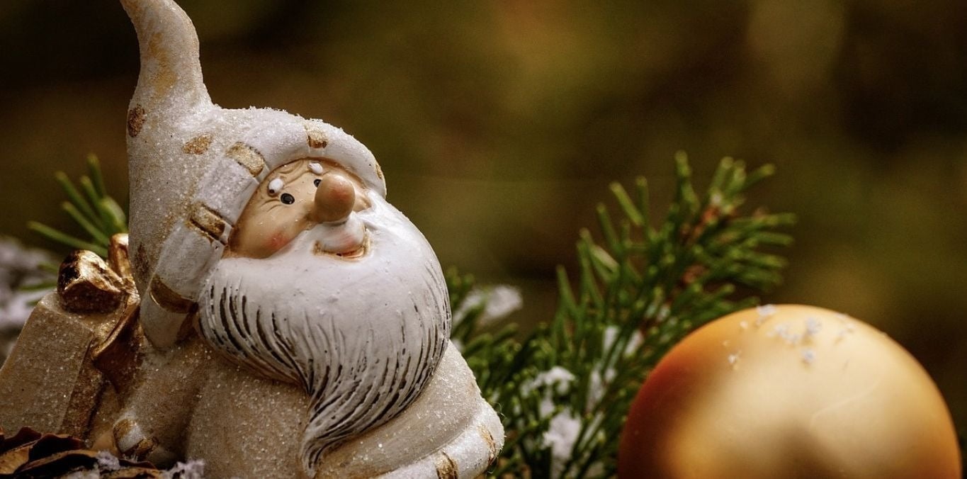 una estatua de santa claus se sienta junto a una bola de navidad