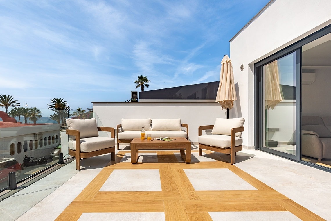 un sofá y dos sillas en un balcón con una mesa y un paraguas