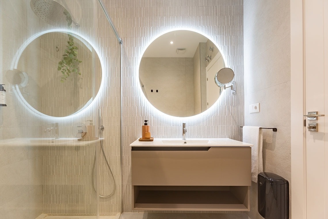 un baño con dos espejos ovales y un lavabo