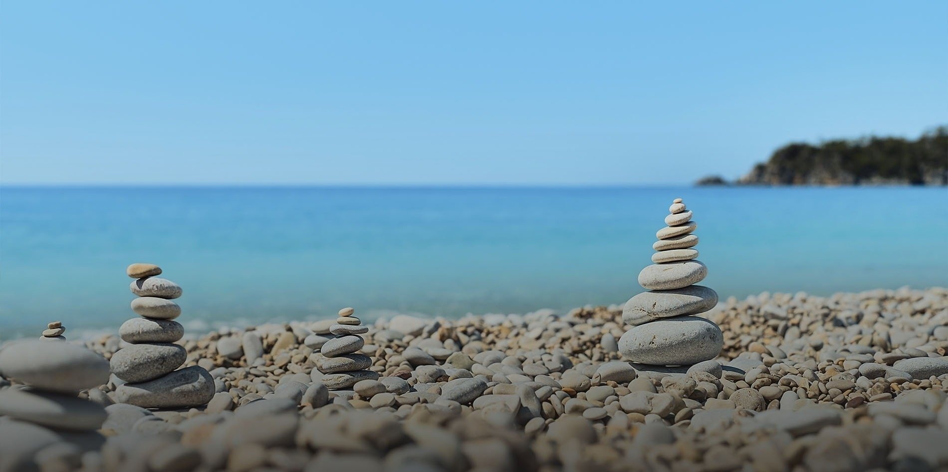 una mujer con sombrero y mochila está parada en la cima de una montaña junto al océano