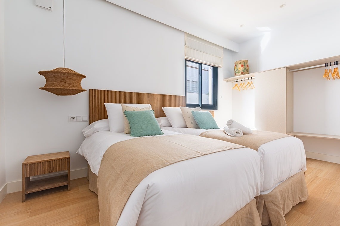 un dormitorio con dos camas y una lámpara colgante