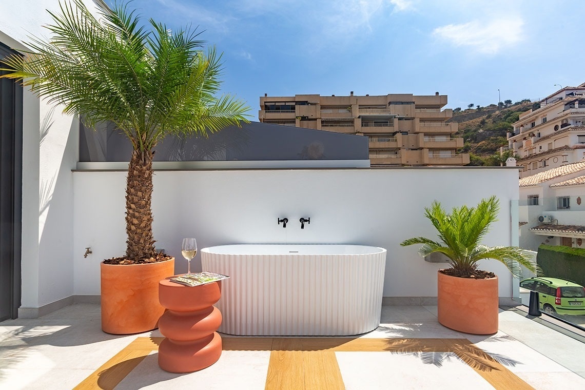 una bañera blanca está rodeada de plantas y una palmera