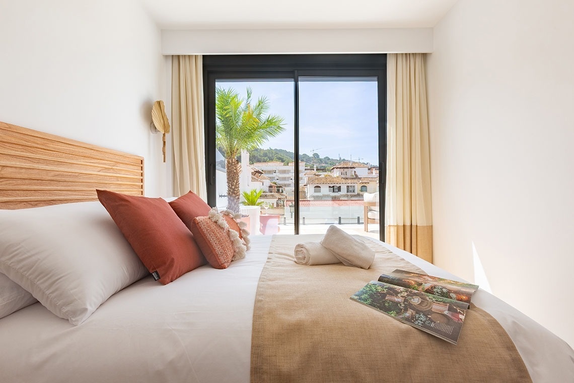 un dormitorio con una cama y una ventana que da al balcón