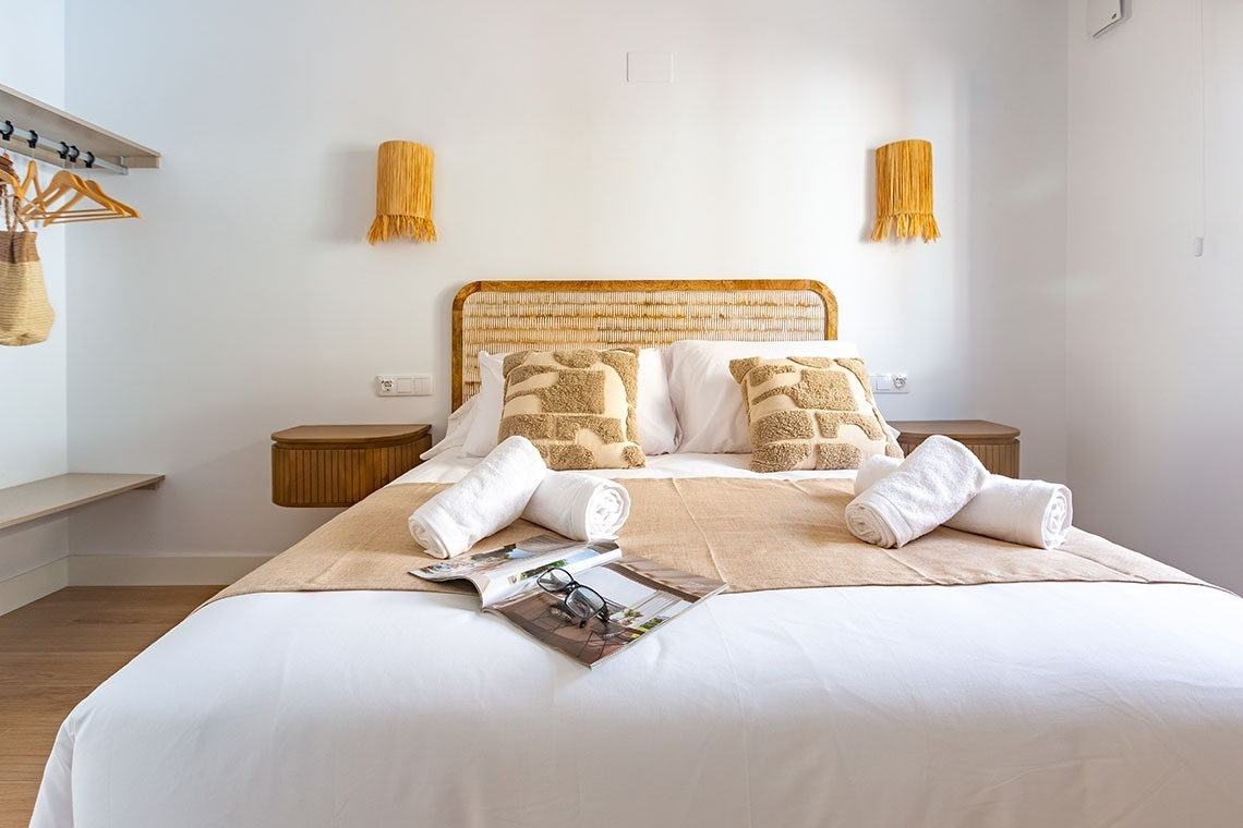 una cama blanca con almohadas y una revista encima