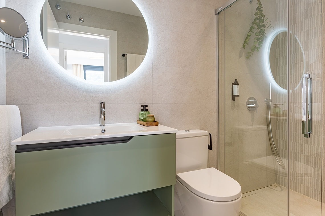 un baño con un lavabo y un inodoro y un espejo redondo