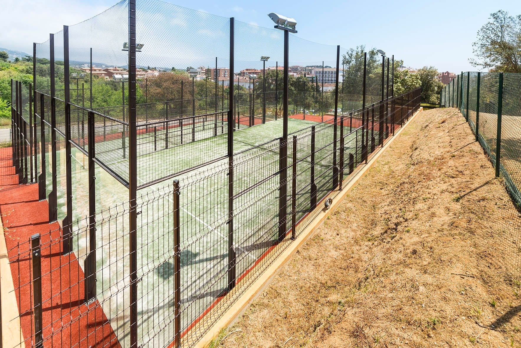 ein grüner Tennisplatz mit einem schwarzen Zaun umgeben