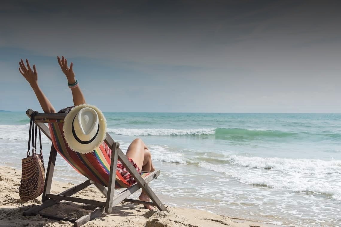 Eine Frau sitzt auf einem Strandstuhl mit ihren Händen in der Luft