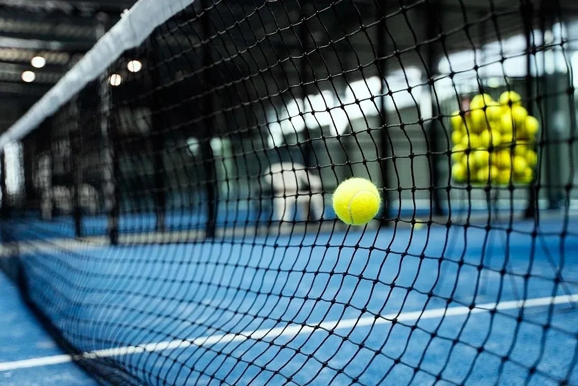 un hombre y una mujer están jugando al pádel en una cancha azul